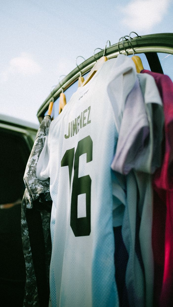 Services A white soccer jersey with the number 16 hangs among colorful clothes on a rack.