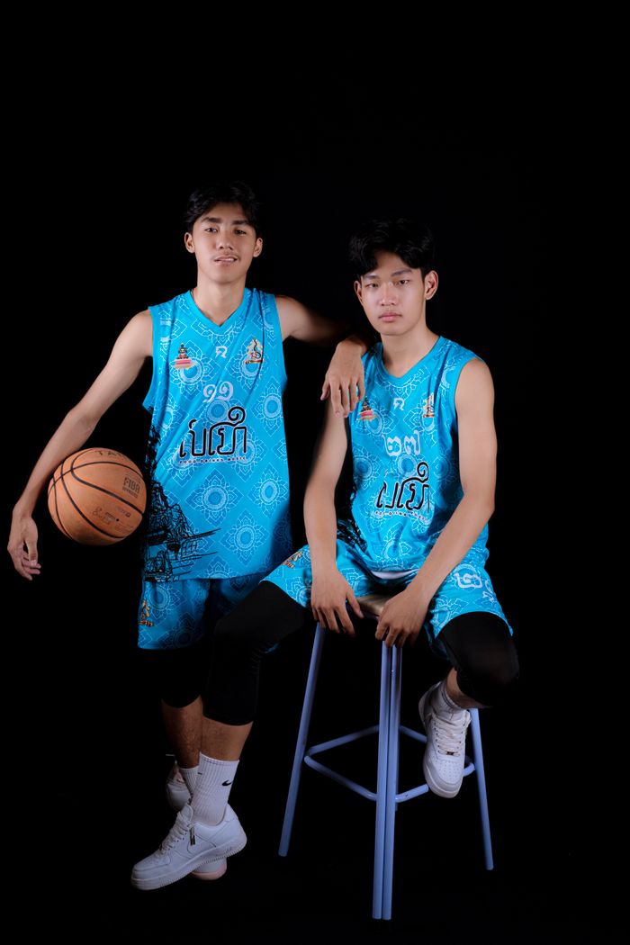 Services Two young male basketball players in blue sportswear posing against a black studio background.