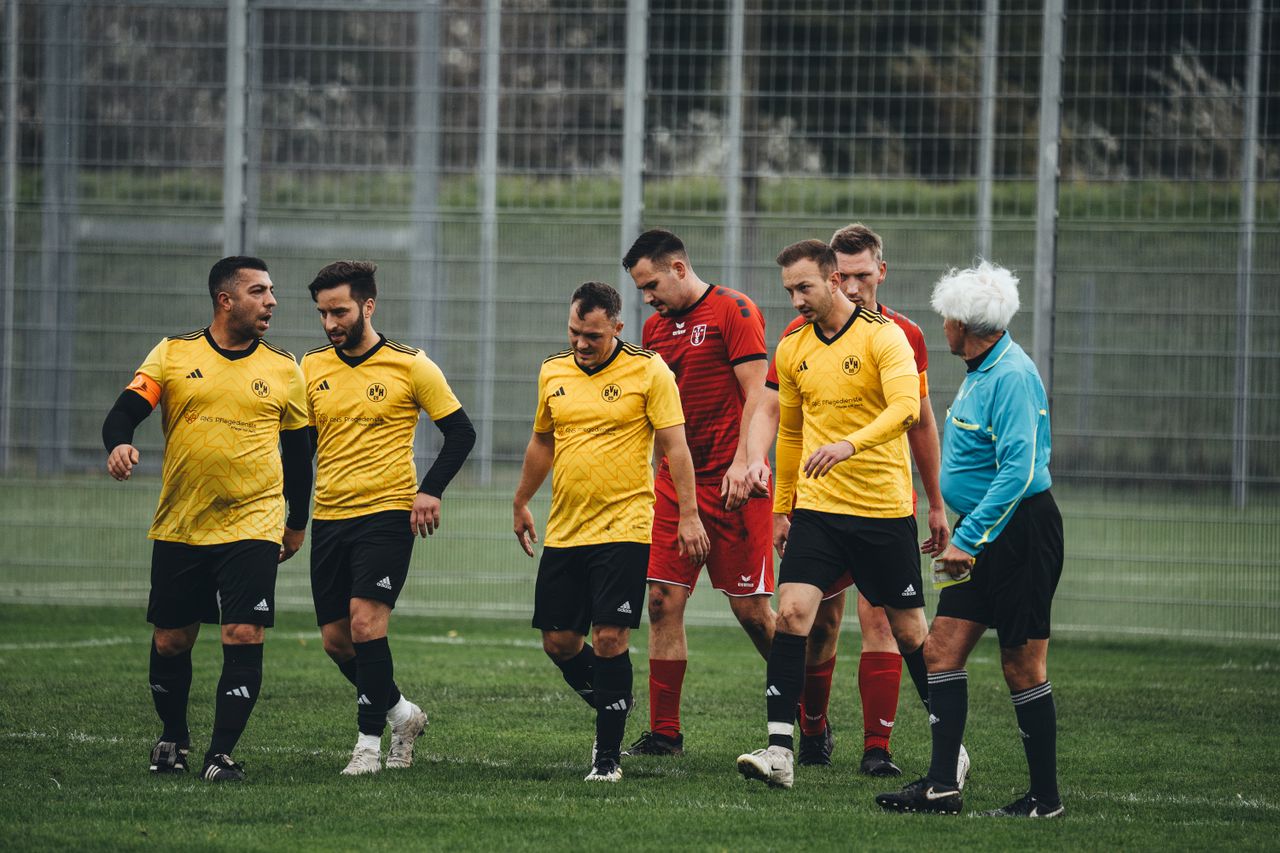 Home Amateur soccer players in yellow uniforms and referee on the field after a match.