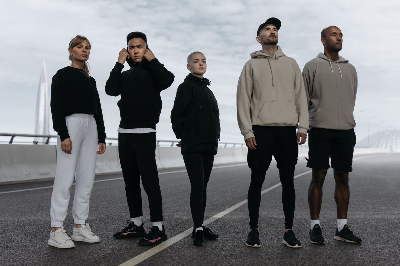 Mastering the First Impression: Your intriguing post title goes here A diverse group of young adults in activewear standing confidently on a road, showcasing modern sports fashion.